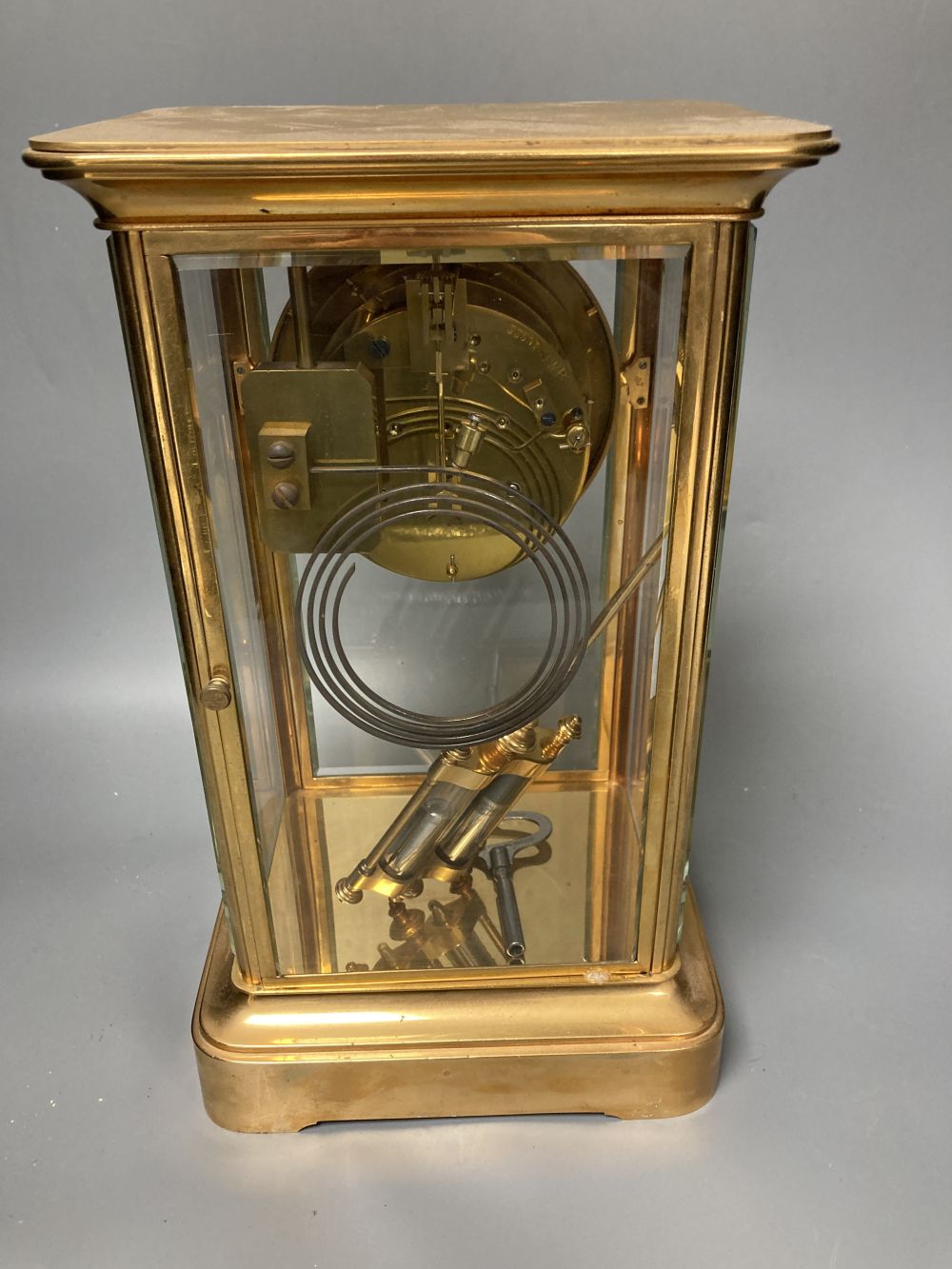 A French brass four glass mantel clock, retailed by J W Benson, with visible Brocot escapement and mercury filled pendulum bob, 33cm hi